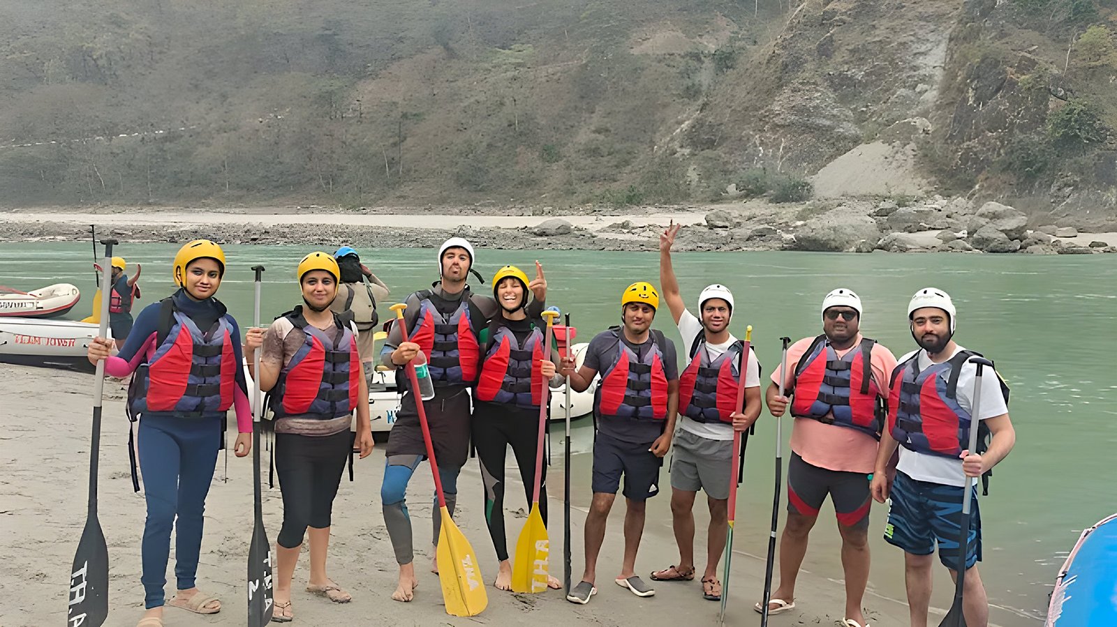 Rafting group with helmets and paddles on the Ganga riverbank, Rishikesh